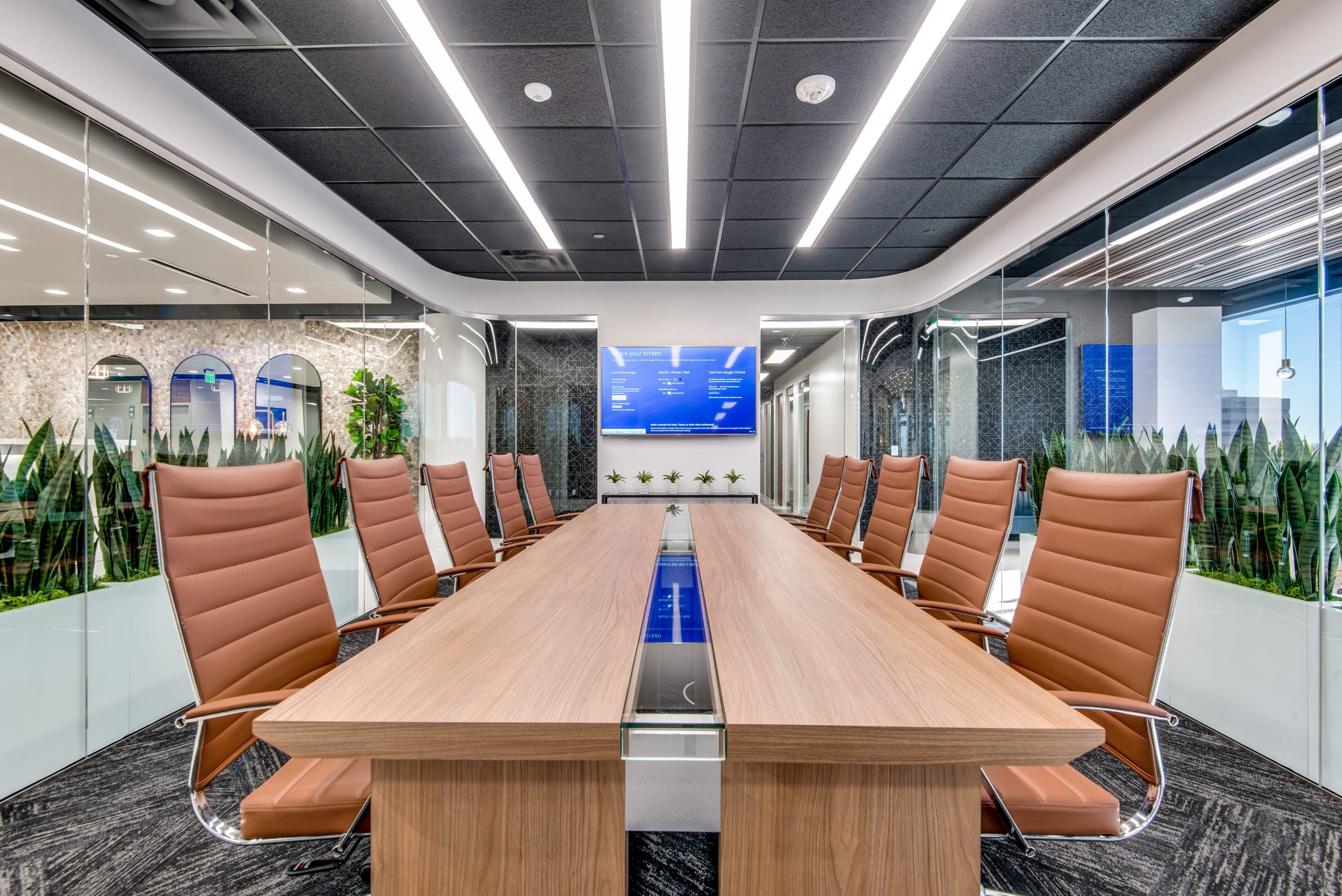 Boardroom with glass windows, a television with screenshare, 8 seats, and modern decor