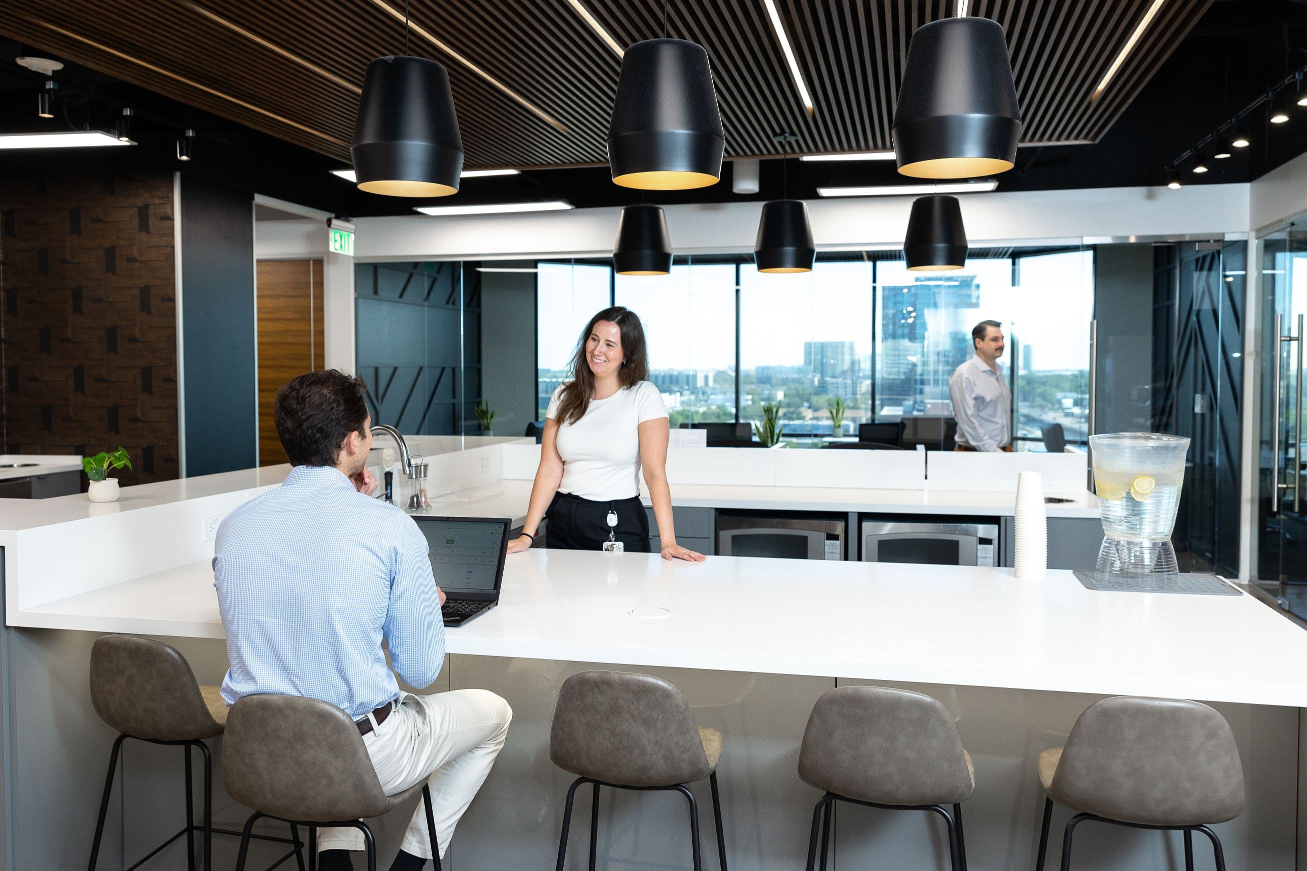 Three people interacting in a coffee lounge at Lucid Private Offices at Uptown / Central Expressway