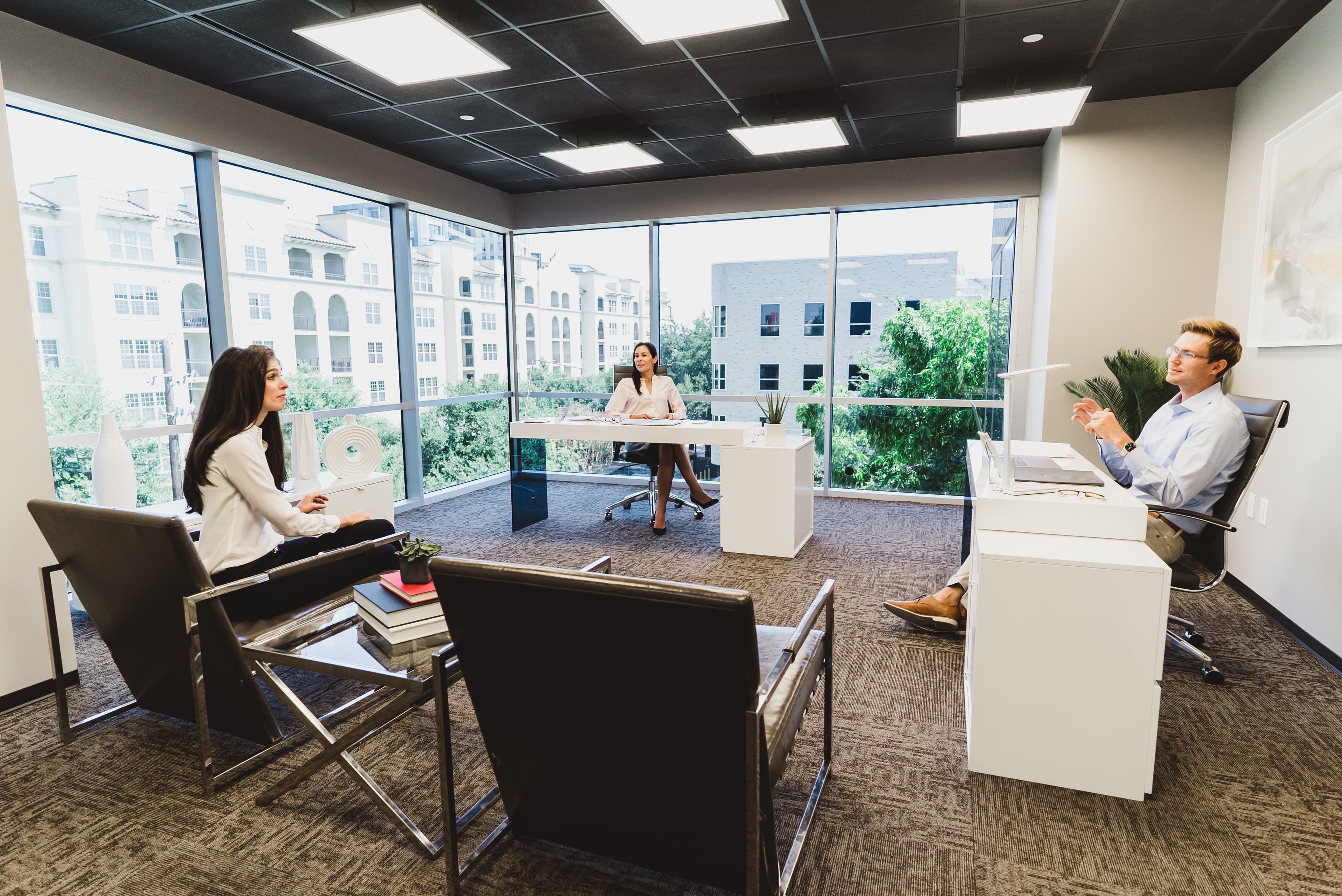 Three people meeting in a corner window office at Lucid Private Offices